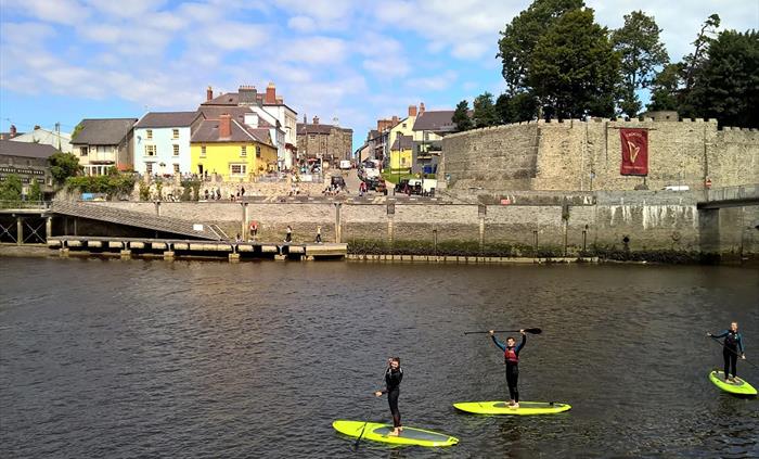 Stand up paddle boarding on the River Teifi in Cardigan by Cardigan Castle